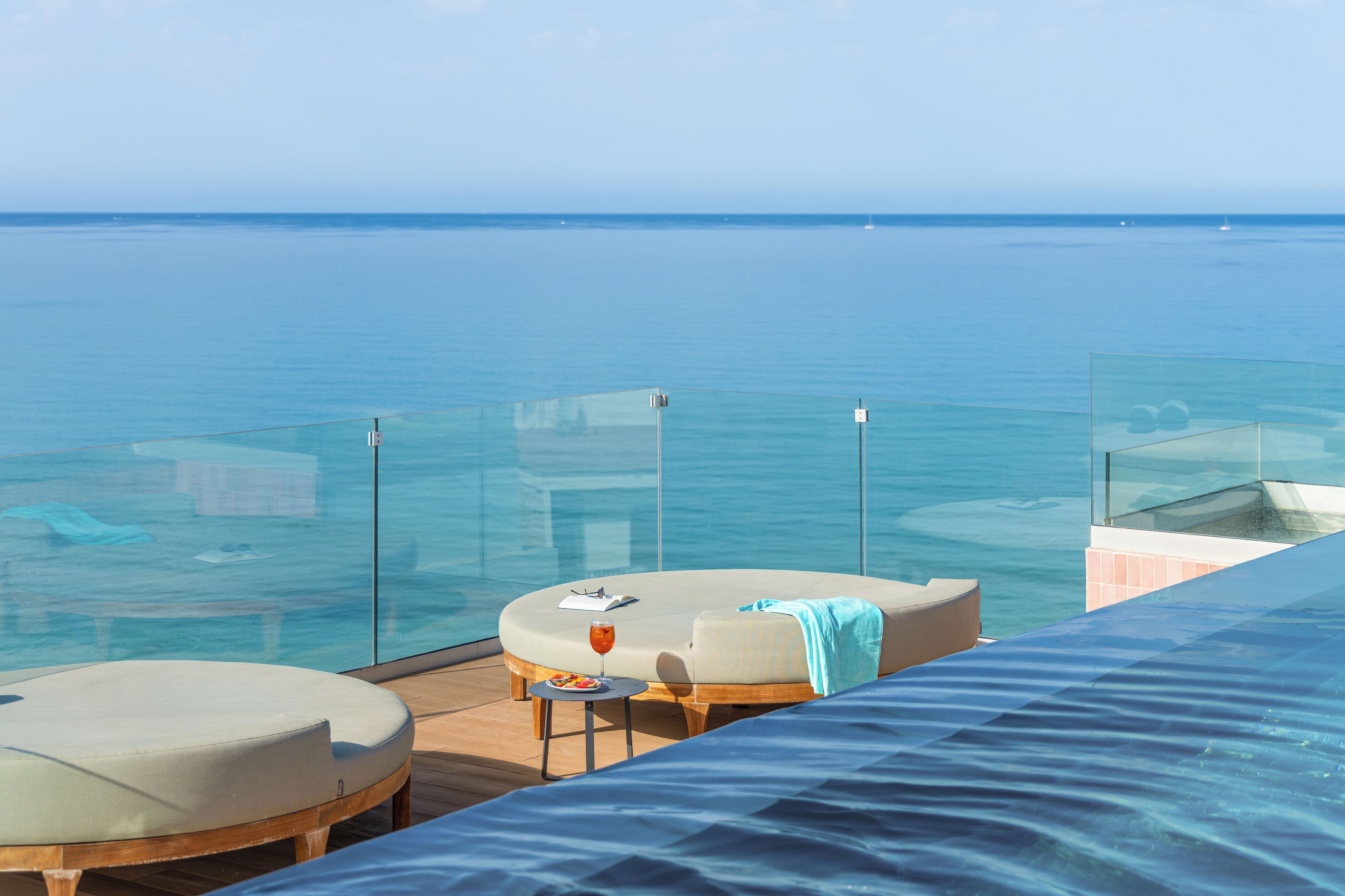 Ein Balkon mit Glastrennwand, der auf ein Gewässer blickt.
