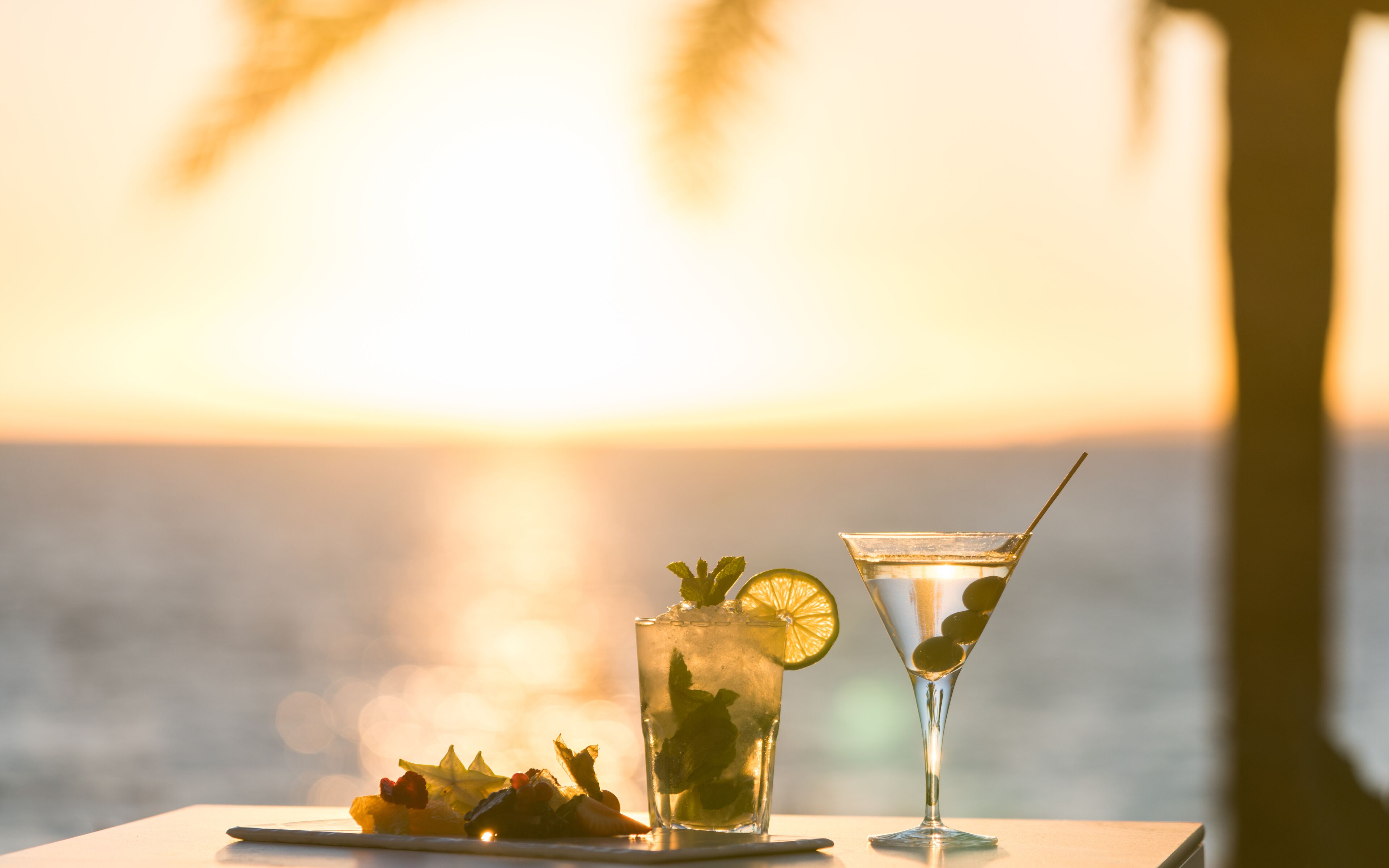 Two drinks on a table with a sunset view.