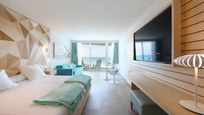 Una habitación de hotel con una cama, un escritorio, un televisor y vistas al océano.