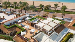 Vista aérea de un resort con zona de piscina, mobiliario exterior y vista a la playa.