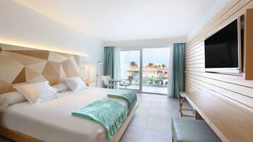 A hotel room with a large bed, a desk, and a view of the outdoor area.