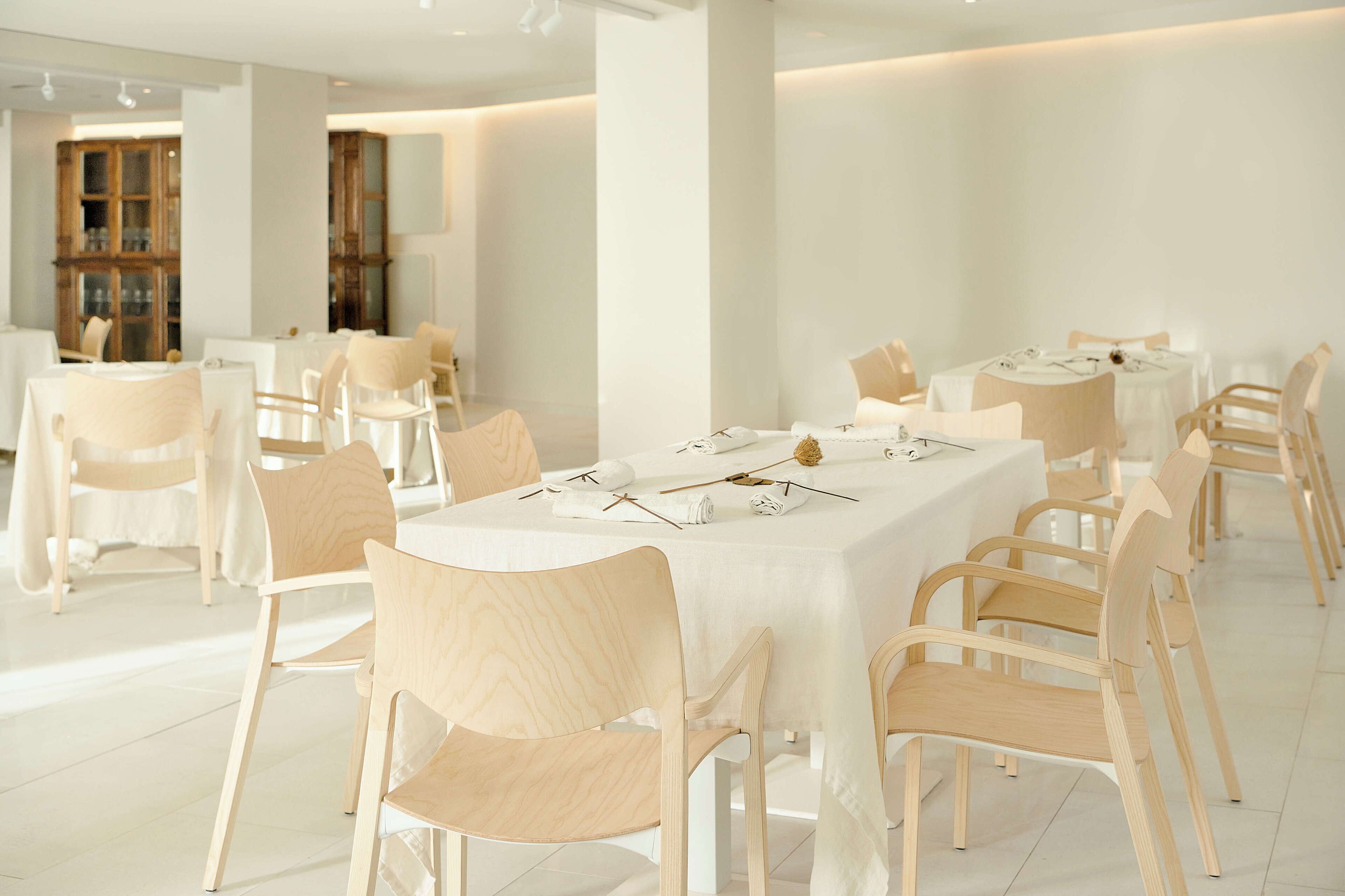 A spacious dining area with white tables and chairs, a polished floor, and a modern interior design.