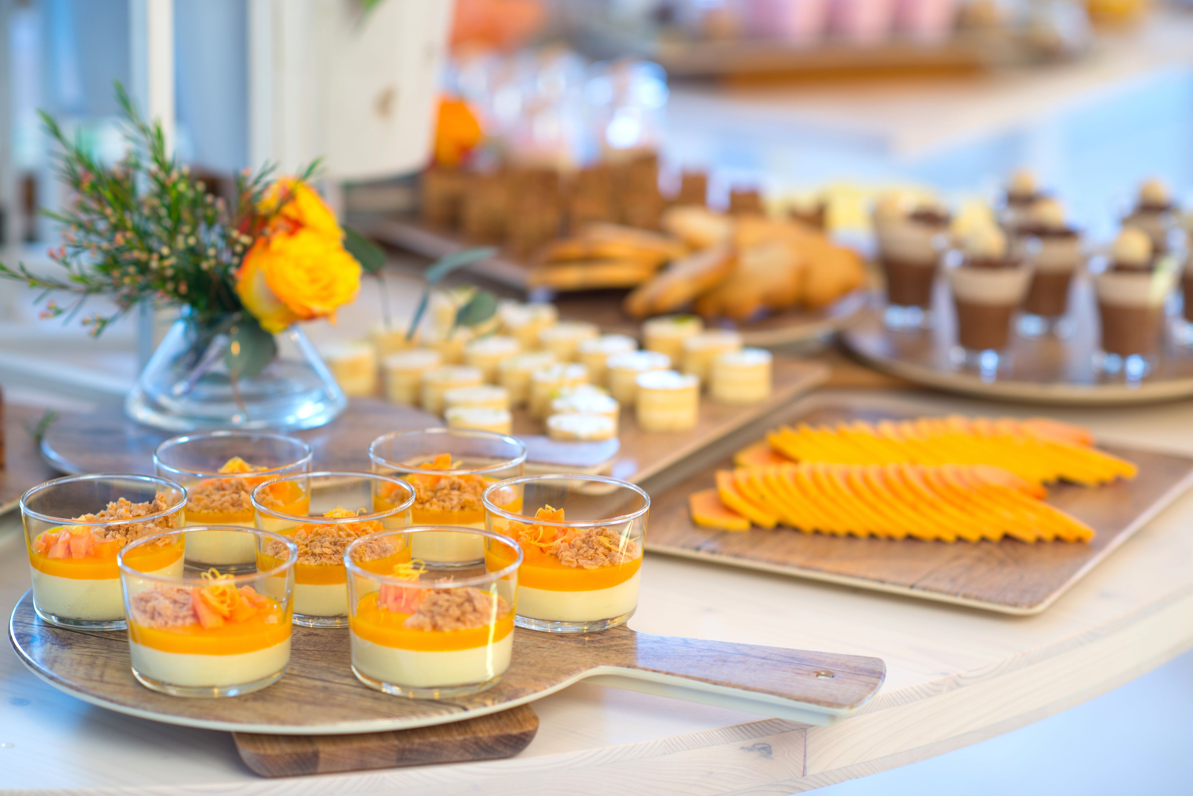 Une table de desserts avec divers mets sucrés et un vase rempli de fleurs.