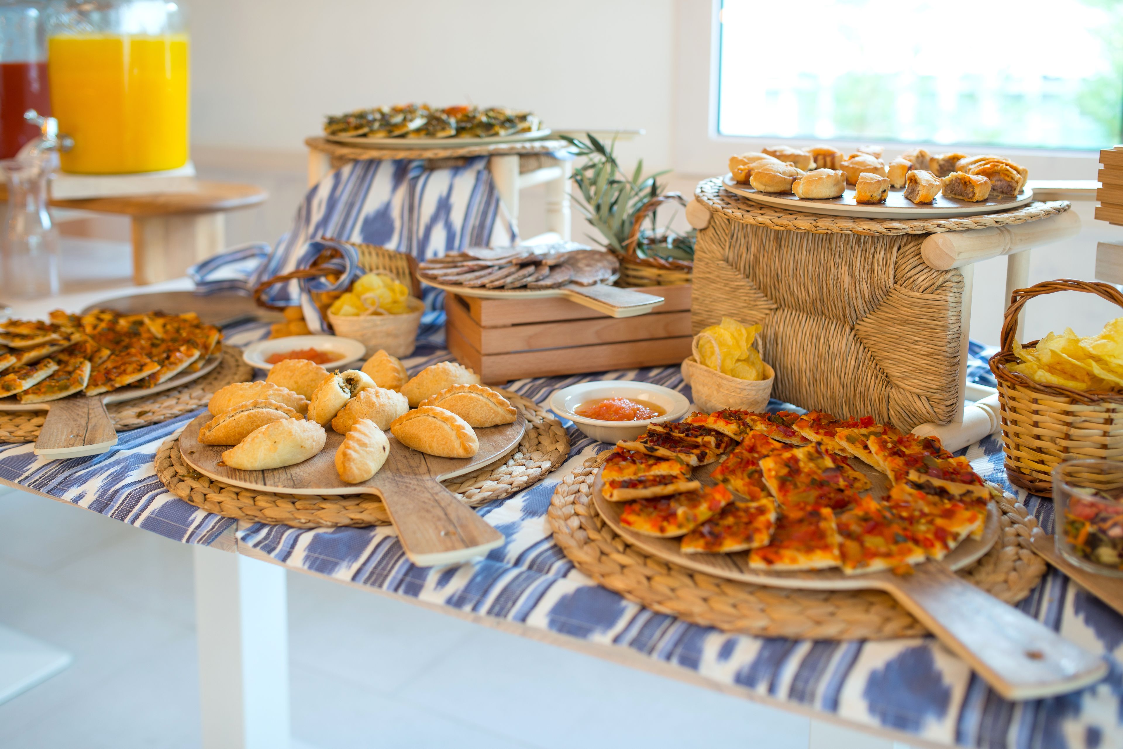 Une table de buffet proposant divers plats, notamment des pâtisseries, du pain et des pizzas.