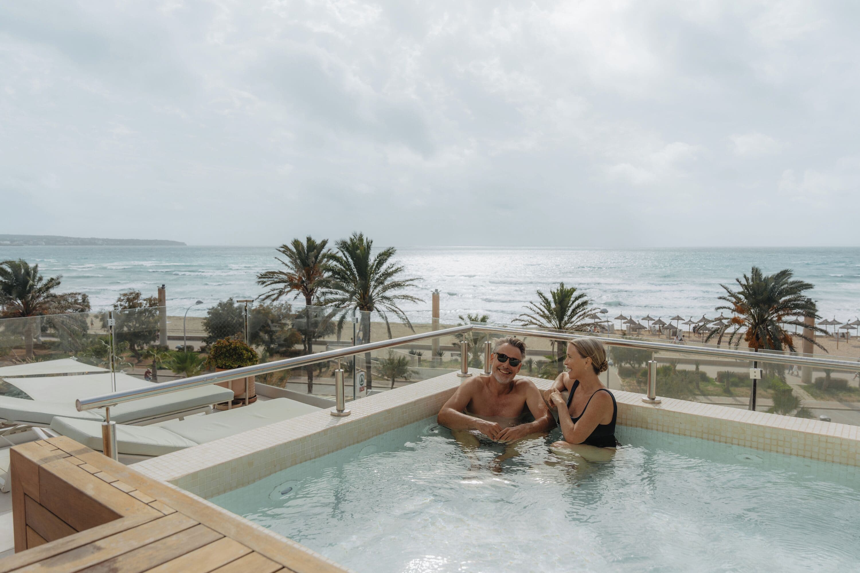 Un couple dans une piscine avec vue sur la plage et l’océan.
