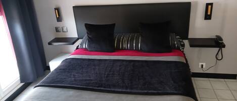 Un letto rifatto con una coperta a righe, due cuscini e un dettaglio rosso.