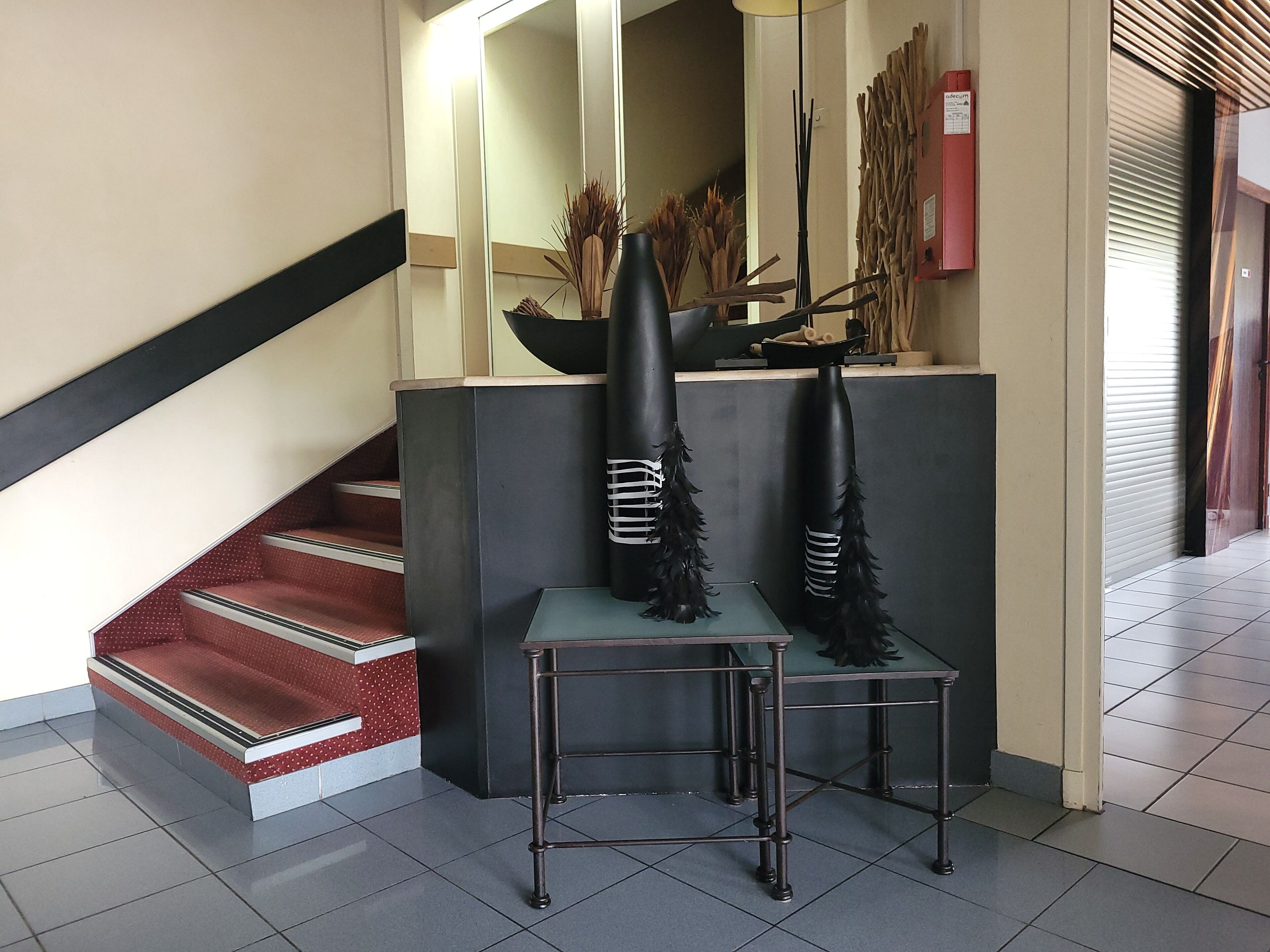 Un área de recepción con una escalera, un mostrador y un espejo.