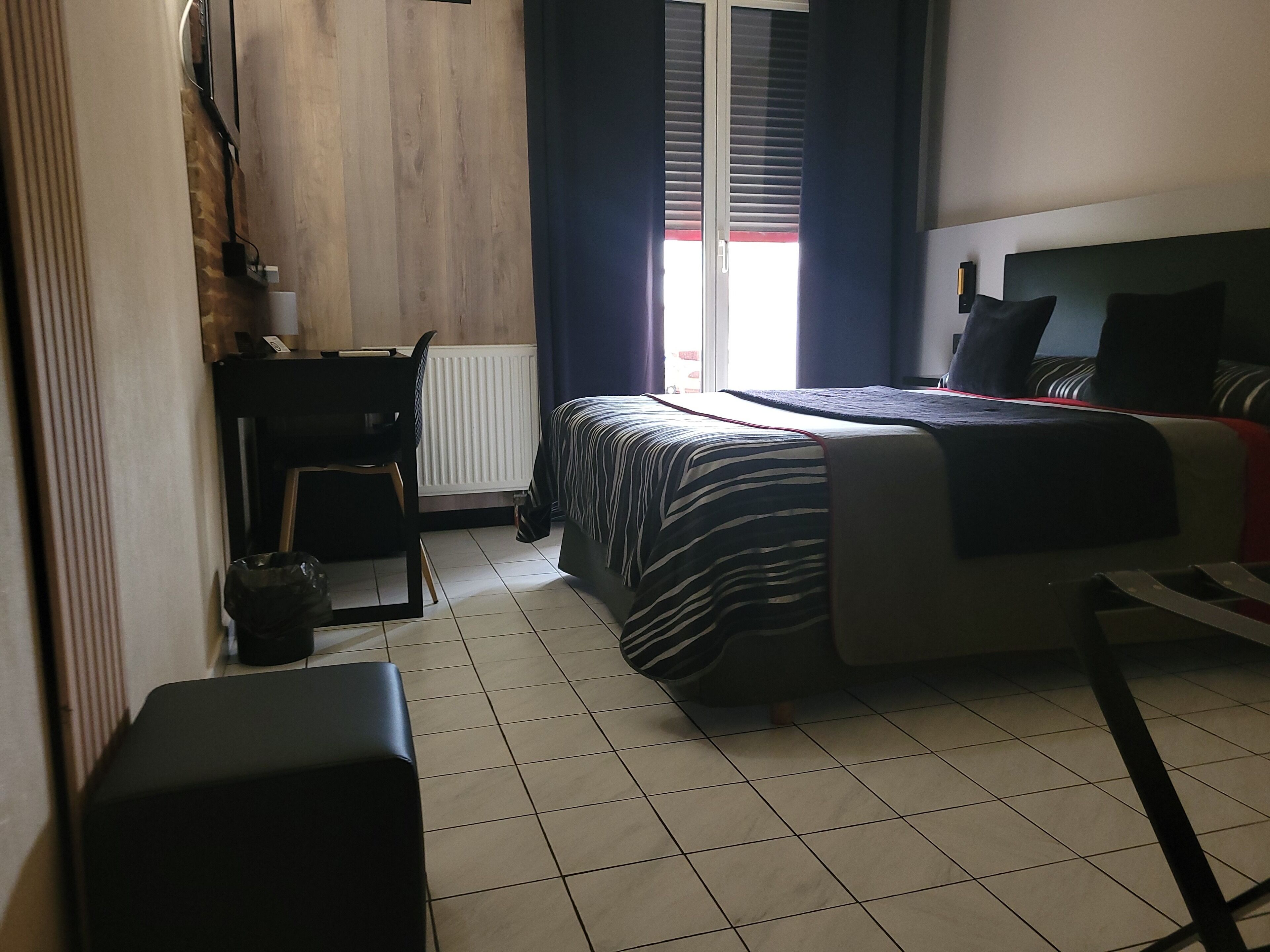 A bedroom with a bed, a desk, a chair, and a radiator.