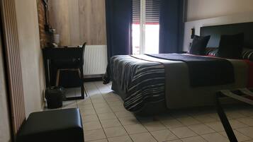 A bedroom with a bed, a desk, a chair, and a radiator.