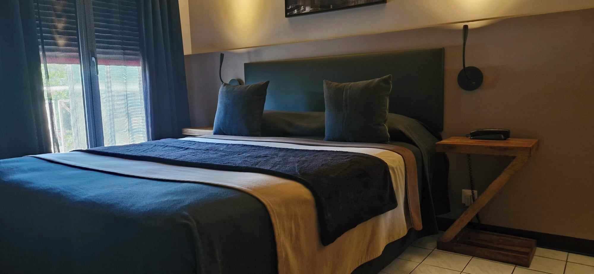 Ein modernes Hotelzimmer mit einem großen Bett, einem Nachttisch und einer Wandlampe.