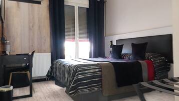 A bedroom with a bed, a desk, and an air conditioning unit.