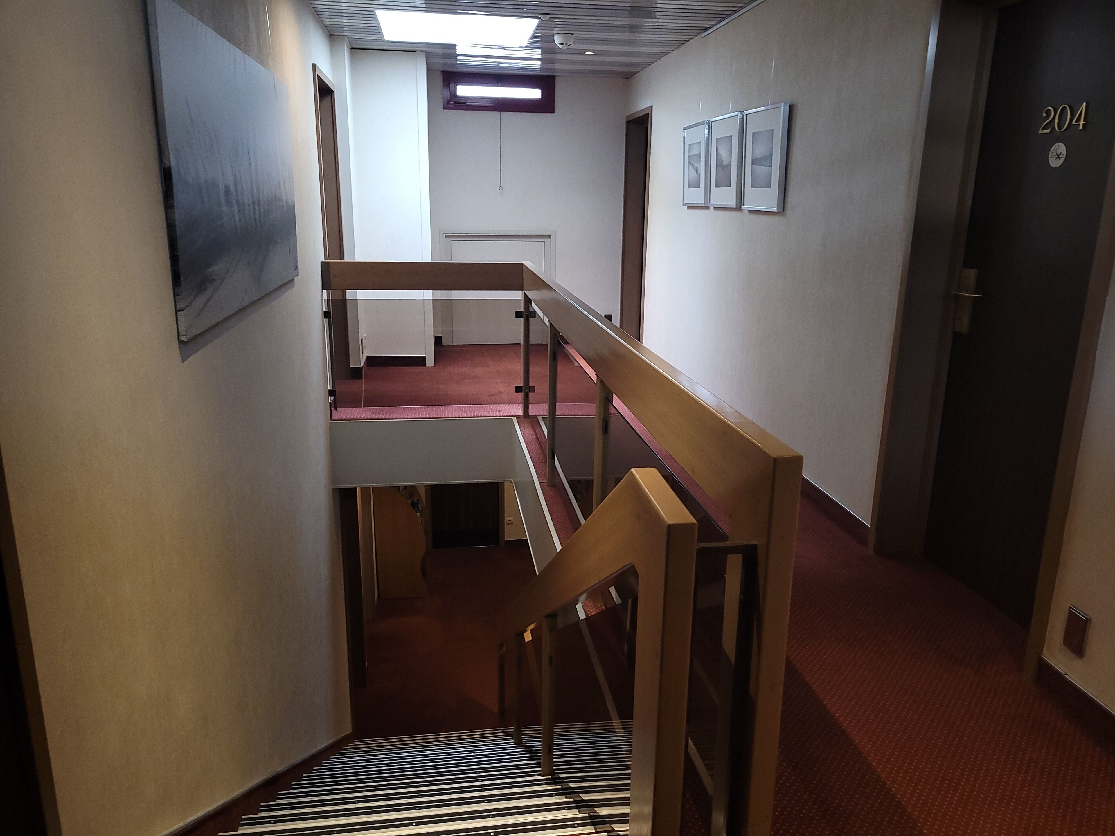 A multi-level interior with a staircase, a door labeled "204", and a red carpeted floor.