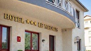 A hotel entrance with a sign reading "HOTEL *** LE MEDICIS".