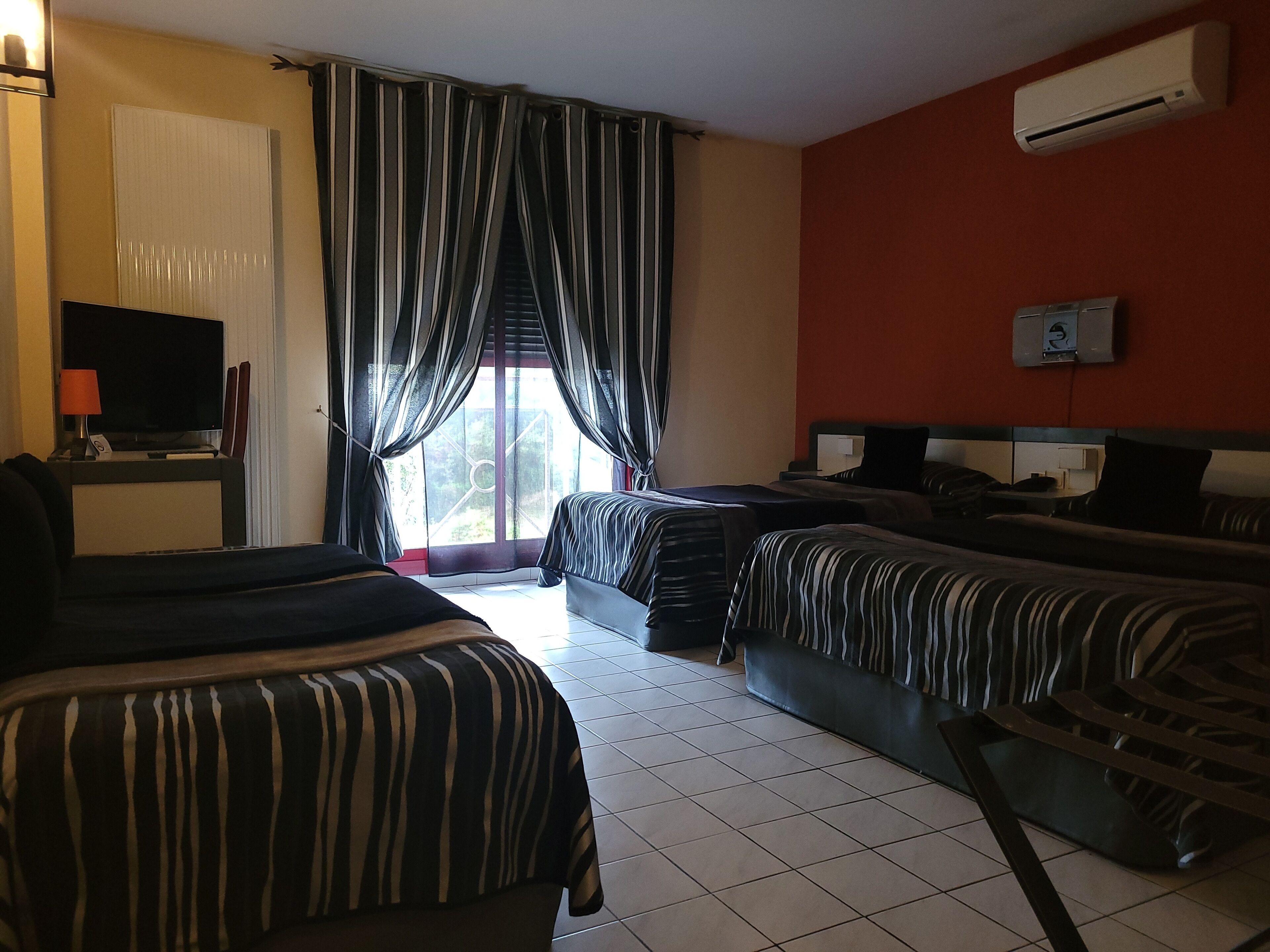 Una habitación de hotel con dos camas, televisión y aire acondicionado.