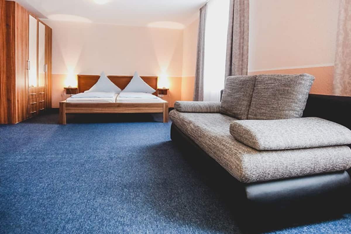 A hotel room with a bed, a sofa, and a wardrobe.