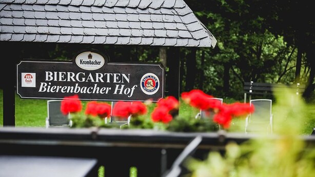 A sign for 'Krombacher Biergarten Bierbacher Hof' with a roof and surrounded by greenery. - Hotel Bierenbacher Hof (Nümbrecht)
