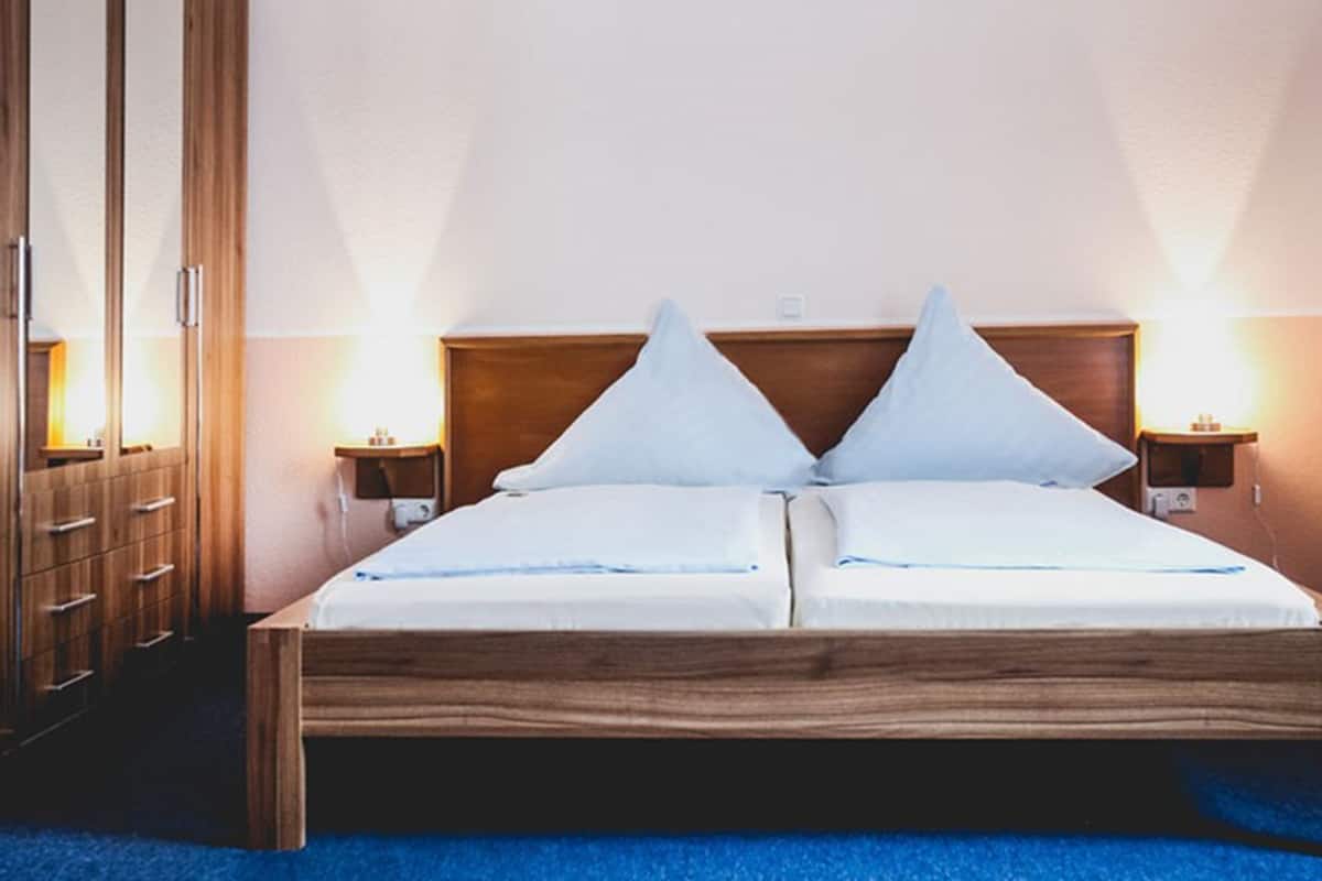 A double bed with wooden headboard, two bedside tables, and a wardrobe with multiple drawers.