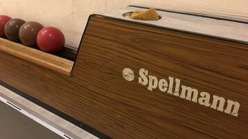 A wooden counter with the name "Spellmann" and a row of bowling balls.