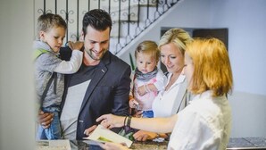 A family of four in a hotel lobby with a staircase in the background. - Hotel Bierenbacher Hof (Nümbrecht)