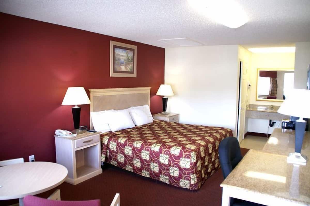 A hotel room with a bed, two bedside tables with lamps, a desk, and a chair.