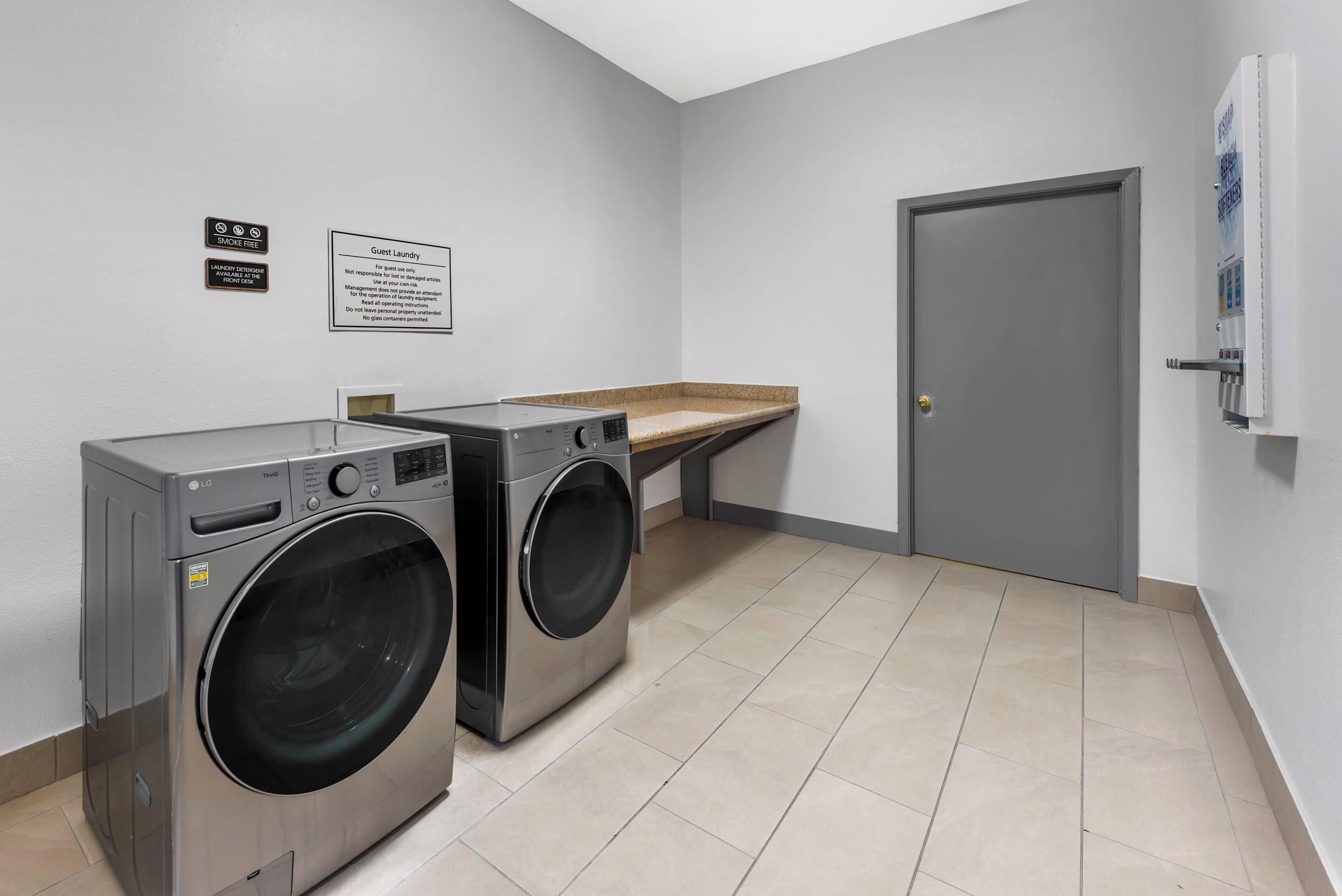A laundry room with two front-loading LG washers, a guest laundry sign, and a door to the right.