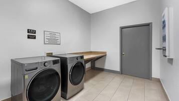 A laundry room with two front-loading LG washers, a guest laundry sign, and a door to the right.