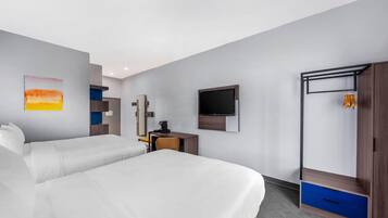 Habitación de hotel con dos camas, un escritorio, televisión y armario.