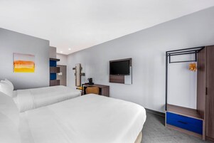 Habitación de hotel con dos camas, un escritorio, televisión y armario.