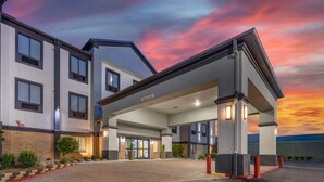 Een moderne hotelentree met een overdekte oprit en een bord waarop 