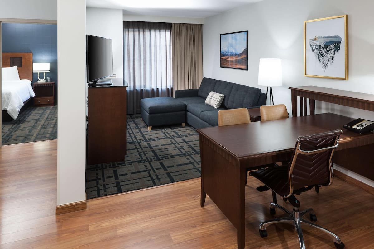 Una habitación de hotel con cama, sofá, escritorio y televisor.