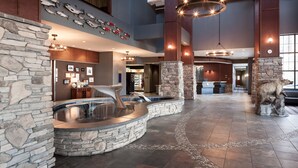 A spacious lobby with a stone fountain, a large fish wall, and a stone bear statue. - Embassy Suites by Hilton Anchorage (Anchorage)