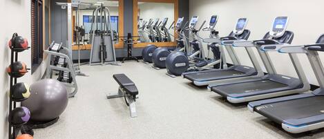 Un gimnasio con cintas de correr, elípticas y pesas libres.