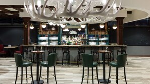 A bar area with a unique chandelier, multiple bar stools, and a well-stocked bar counter. - Embassy Suites by Hilton Anchorage (Anchorage)