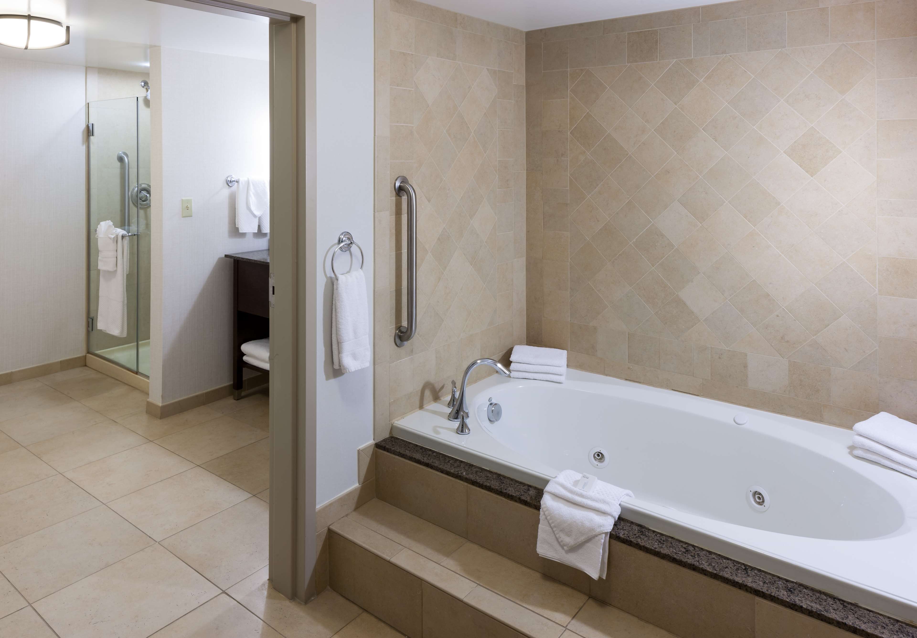 A modern bathroom with a large bathtub, a glass shower enclosure, and a vanity with a towel rack.