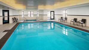 Ein Innenpool mit klarem Wasser, umgeben von Stühlen und gefliestem Boden.