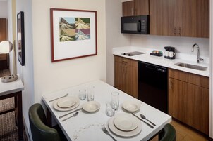 A modern kitchen with a white countertop, a microwave, a coffee maker, and a sink.