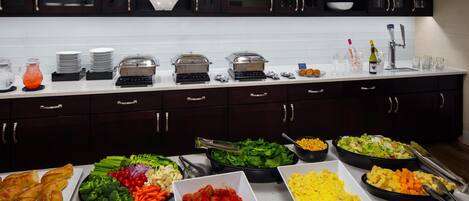 A buffet setup with various food items and kitchenware.