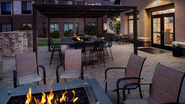 Ein Patio mit Feuerstelle, Sitzgelegenheiten im Freien und einem überdachten Essbereich.