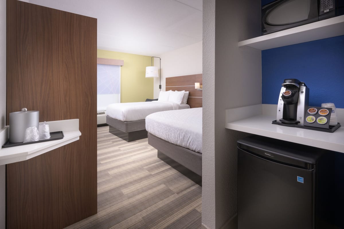 Une chambre d’hôtel avec deux lits, une machine à café, un four à micro-ondes et un petit réfrigérateur.