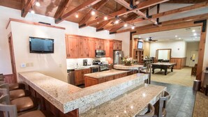 A spacious kitchen with granite countertops, wooden cabinets, and a bar area with stools. - Mountain Retreat Resort (Arnold)