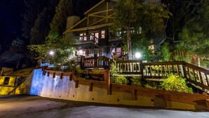 A multi-story building with balconies and outdoor seating areas, surrounded by trees and a concrete wall. - Mountain Retreat Resort (Arnold)
