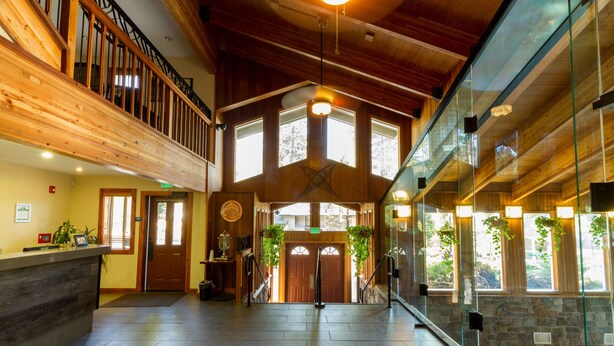 A spacious lobby with a wooden reception desk, a staircase, and large windows allowing natural light. - Mountain Retreat Resort (Arnold)