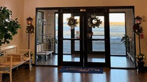 A hotel lobby with a wooden bench, a reception desk, a chandelier, and a view of the beach through the entrance doors. - Baymont by Wyndham Limon (Limon)