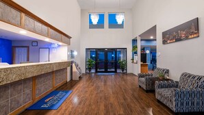 A hotel reception area with a reception desk, seating area, and a cityscape view. - Baymont by Wyndham Limon (Limon)