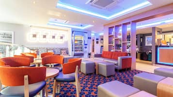 A hotel lobby with seating areas, a bar, and a reception desk.