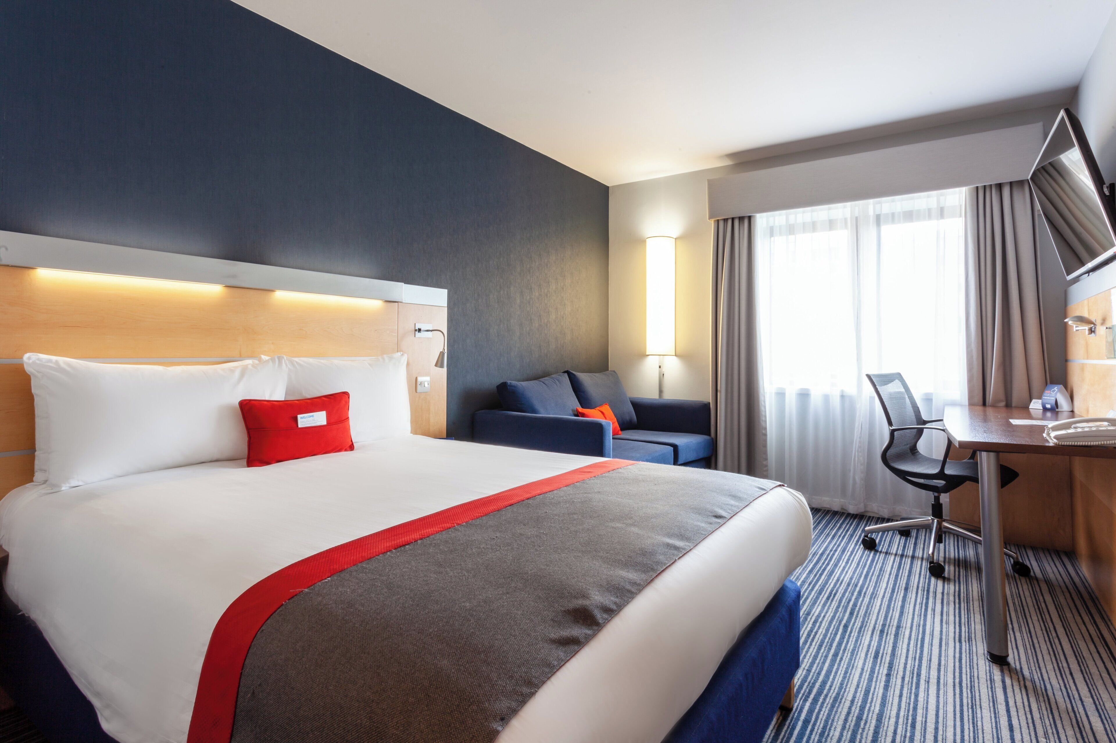 Ein Hotelzimmer mit einem großen Bett, einem Schreibtisch, einem Stuhl und einer Couch.