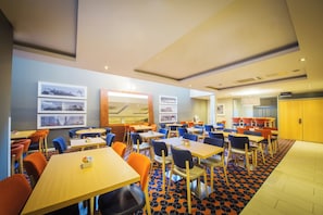 A hotel dining area with multiple tables and chairs, a patterned floor, and framed pictures on the walls. - Holiday Inn Express Edinburgh Royal Mile by IHG (Edinburgh)