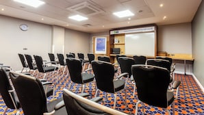 A conference room with rows of chairs, a whiteboard, a clock, and a digital screen. - Holiday Inn Express Edinburgh Royal Mile by IHG (Edinburgh)