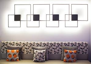 A modern living room with a geometric-patterned sofa and a series of framed artworks on the wall. - Holiday Inn Express Edinburgh Royal Mile by IHG (Edinburgh)