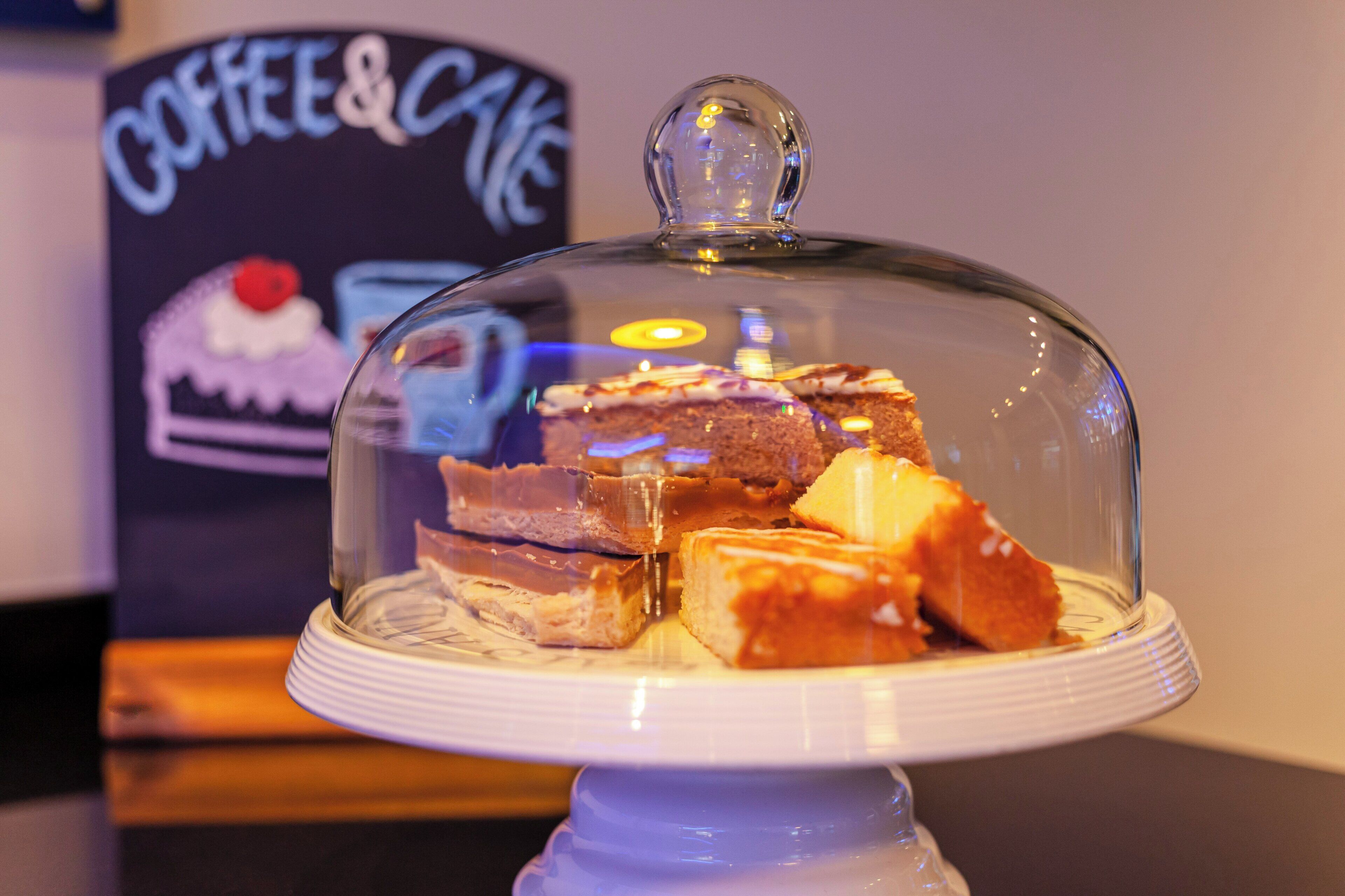 A dessert display with a glass dome cover, featuring various cakes and pastries.